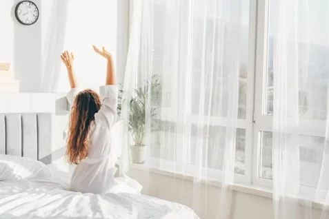 Mujer levantándose con cortinas automáticas